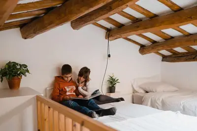 two people sitting on a bed reading books at Ca l'Espavil in Cardedeu