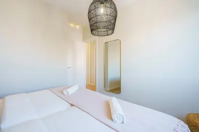 a white bedroom with a bed and a mirror at Sitges Spaces Mediterranean Penthouse in Sitges