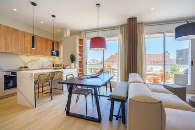 a kitchen and living room with a table and a couch at Sitges Spaces Mediterranean Penthouse in Sitges