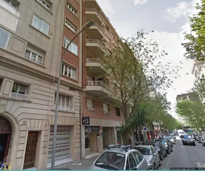 a tall building with cars parked next to a street at Letsgo Camp Nou Apartment in Barcelona