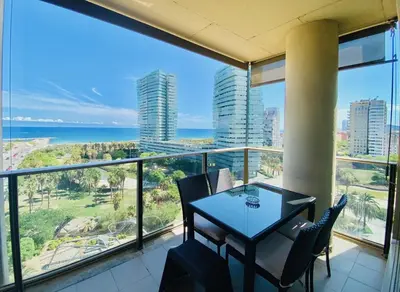 a balcony with a table and chairs and the ocean at Akira Flats Diagonal Mar Apartments in Barcelona