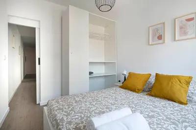 a white bedroom with a large bed with yellow pillows at APARTMENT BEACH PICASSO in Sant Adria de Besos