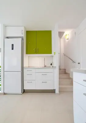 a white kitchen with green cabinets and a refrigerator at Tranquil Duplex Sitges, sea views, private parking, terrace in Sitges