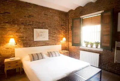 a bedroom with a white bed and a brick wall at The Patio Barcelona in Barcelona