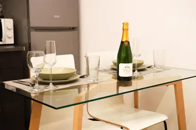 a glass table with a bottle of wine and glasses at Cozy near the Barcelona Camp Nou Stadium in Barcelona