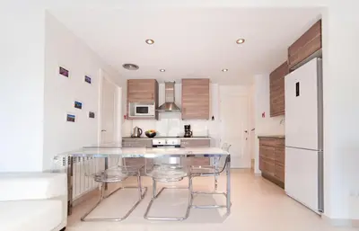 a kitchen with a glass table and a refrigerator at Modern Duplex in Sitges with Private Parking, Sea Views & Terrace in Sitges