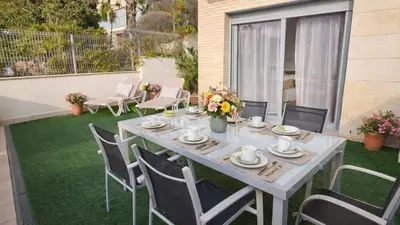 a table and chairs on a patio with grass at Modern Duplex in Sitges with Private Parking, Sea Views & Terrace in Sitges
