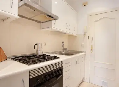 a white kitchen with a stove and a sink at GuestReady - Charming simplicity near Casa Milà in Barcelona