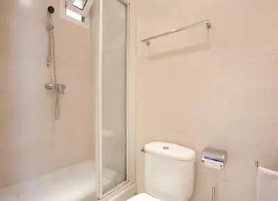 a white bathroom with a shower and a toilet at GuestReady - Charming simplicity near Casa Milà in Barcelona