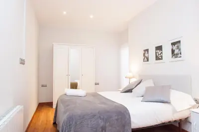 a white bedroom with a large white bed in it at Autèntic Arc de Triomf Apartment in Barcelona