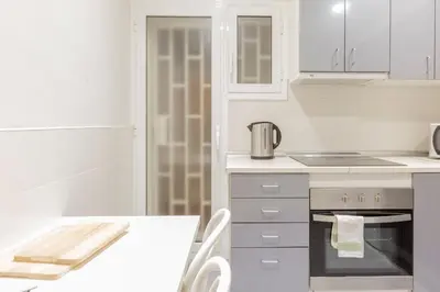 a white kitchen with white cabinets and a table at Autèntic Arc de Triomf Apartment in Barcelona