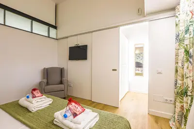 a room with two beds and a chair and a television at Alcam Les Corts in Barcelona