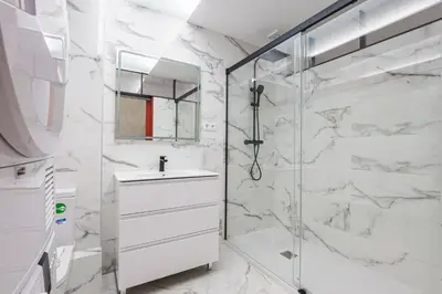 a white bathroom with a shower and a sink at Alcam Les Corts in Barcelona