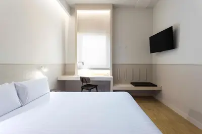 a bedroom with a bed and a desk and a television at Hotel Terrassa Confort in Terrassa