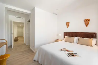 a white bedroom with a large bed and a hallway at Calella Apartments by Olala Homes in Calella