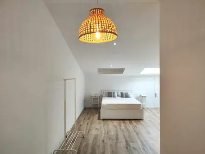 a white bedroom with a bed and a chandelier at Mazi Apartments Cuba in Mataró