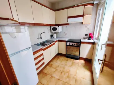 a small kitchen with white cabinets and a refrigerator at Amplio apartamento con terraza in Hospitalet de Llobregat