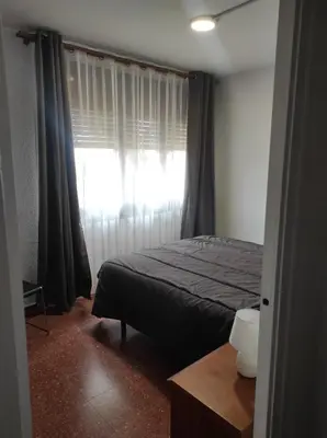 a bedroom with a bed and a window with curtains at Apartamentos Can Bruguera 4 in Mataró