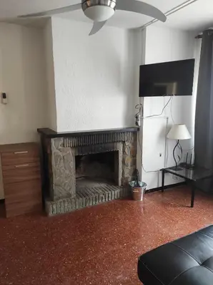 a living room with a stone fireplace with a television at Apartamentos Can Bruguera 4 in Mataró