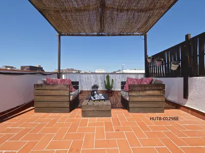 a patio with two couches and a fire pit on a roof at Sunny Rooftop Apartment in Barcelona