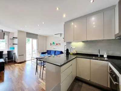 a kitchen with white cabinets and a dining room at Teatro Miro Apartment in Barcelona