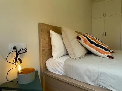 a bed with pillows and a lamp on a table at Superflat near beach 15' center in Sant Adria de Besos