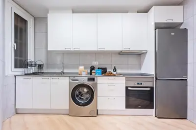 a kitchen with white cabinets and a washing machine at Sweett - Casa Miro in Barcelona