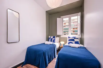 two blue and white beds in a room with a window at Sweett - Casa Miro in Barcelona