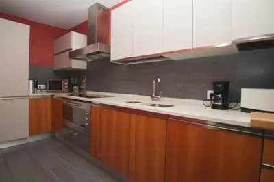 a kitchen with white and wooden cabinets and a sink at Luxury Central Apartment in Barcelona
