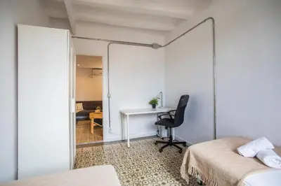 a bedroom with two beds and a desk and a chair at BBarcelona Sants Flat in Barcelona