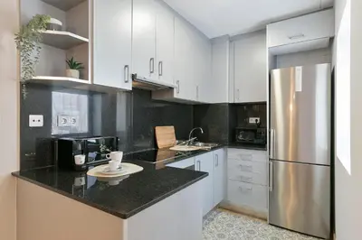 a kitchen with white cabinets and a stainless steel refrigerator at Click&Flat Sugranyes in Barcelona