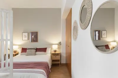 a white bedroom with a bed and a mirror at Click&Flat Sugranyes in Barcelona