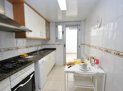 a white kitchen with a sink and a table at Gaudi Contemporani in Mataró
