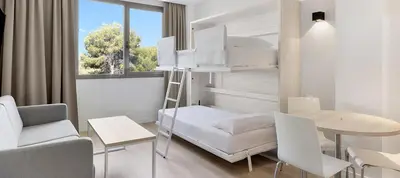 a room with a bunk bed and a desk and a table at B&B HOTEL Barcelona Sant Cugat in Sant Cugat del Vallès