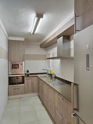 a kitchen with stainless steel appliances and wooden cabinets at Family apartment Besos in Sant Adria de Besos