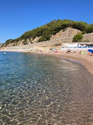 a beach with people laying on the sand and the water at Casa con vista y jardín, a 20' de la playa in Sant Cebrià de Vallalta