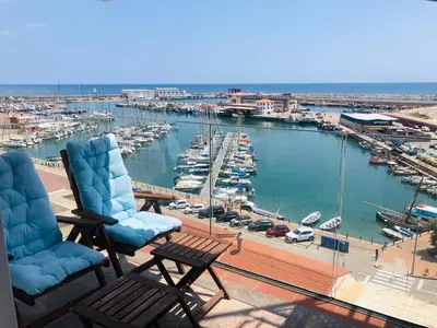a balcony with two chairs and a marina with boats at Apartamento playa in Arenys de Mar