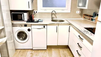 a white kitchen with a washing machine and a sink at Apartamento playa in Arenys de Mar