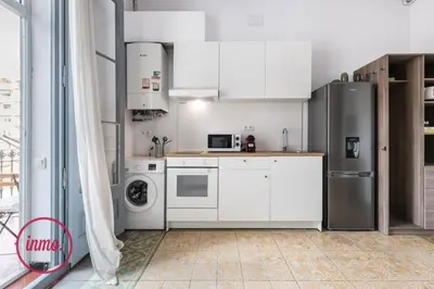 a kitchen with white cabinets and a stainless steel refrigerator at Barcelona - Eixample 2 in Barcelona