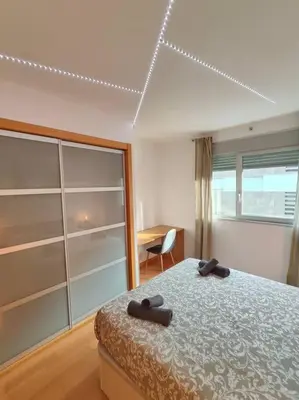 a bedroom with a bed and a desk and a chair at Cozy apartment Forum beach in Sant Adria de Besos