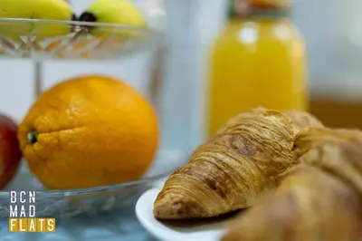 a plate with a croissant and an orange and a bowl of fruit at Bcn - Sagrada Familia in Barcelona