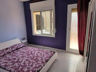 a bedroom with a bed with purple walls and a window at La casita de Pe Beach in Premiá de Mar