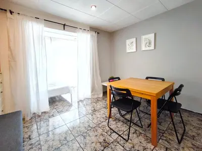 a table and chairs in a room with a window at Apartamento loft en Castelldefels junto la playa in Castelldefels