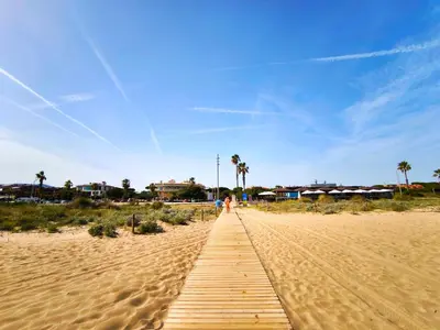 a wooden path through the sand on a beach at Apartamento loft en Castelldefels junto la playa in Castelldefels