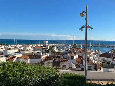 a city with houses and a street light and the ocean at Sitges Port View Apartment by Hello Homes Sitges in Sitges