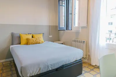 a bedroom with a bed with yellow pillows and a window at Aticco Living Gràcia - Apartments Rooftop in Barcelona