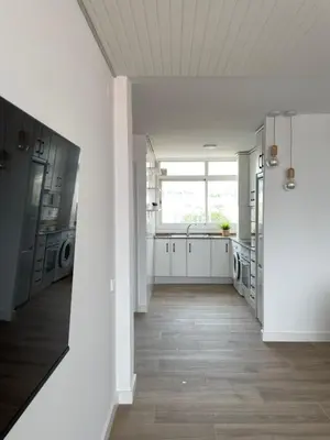 a kitchen with white cabinets and a wooden floor at Apartment Llavaneres near Barcelona Beach Pool in Sant Andreu de Llavaneres