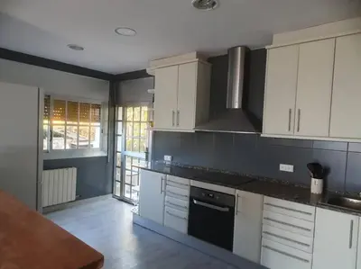 a kitchen with white cabinets and a stove top oven at Casa con gran jardín y unas preciosas vistas in Teià