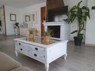 a white coffee table in a living room with a fireplace at Casa con gran jardín y unas preciosas vistas in Teià