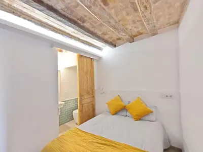 a bedroom with white walls and a bed with yellow pillows at Antic Manresa 2 in Manresa